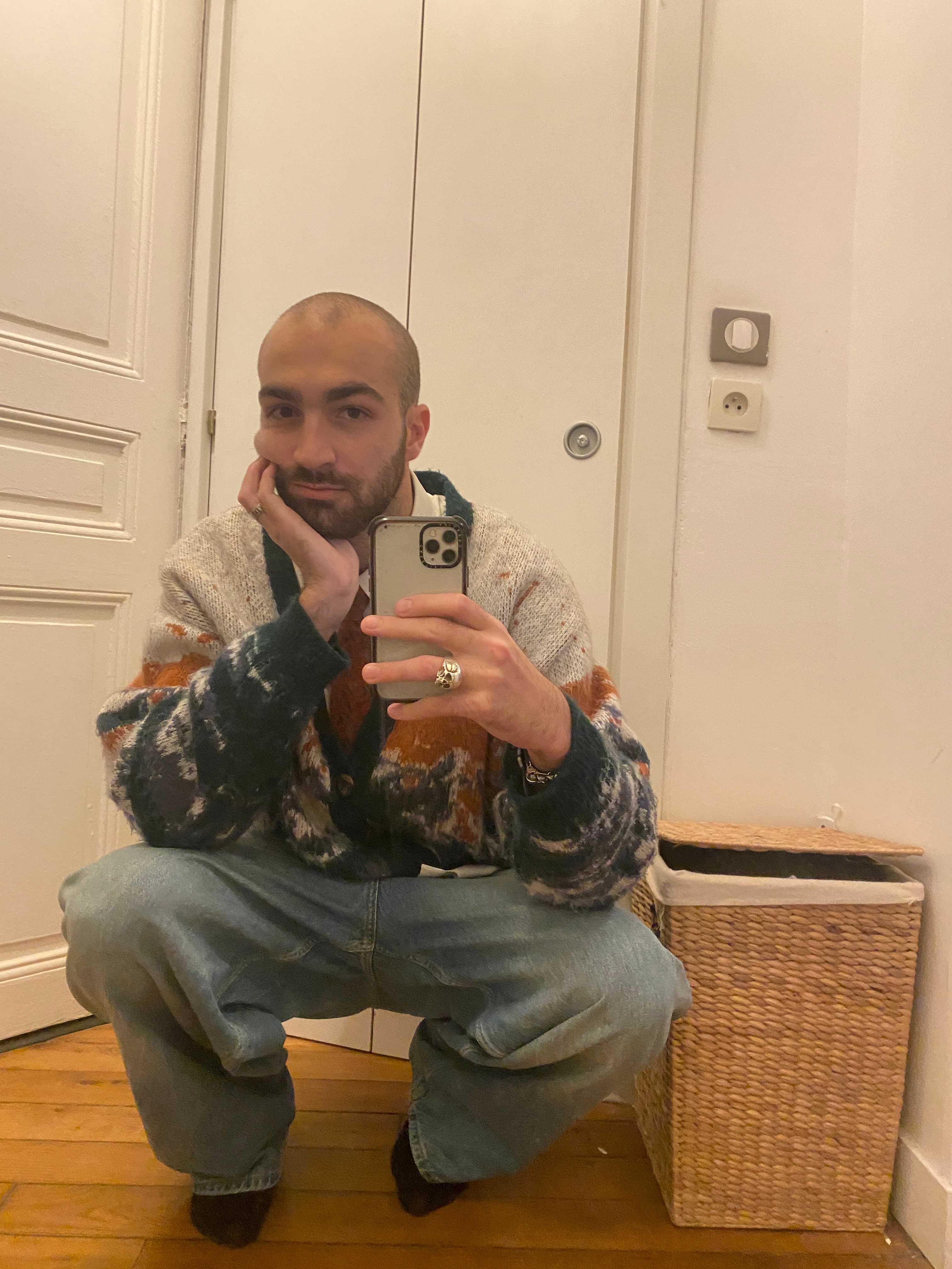 Arthur taking a mirror portrait, sitting in a patterned wool cardigan