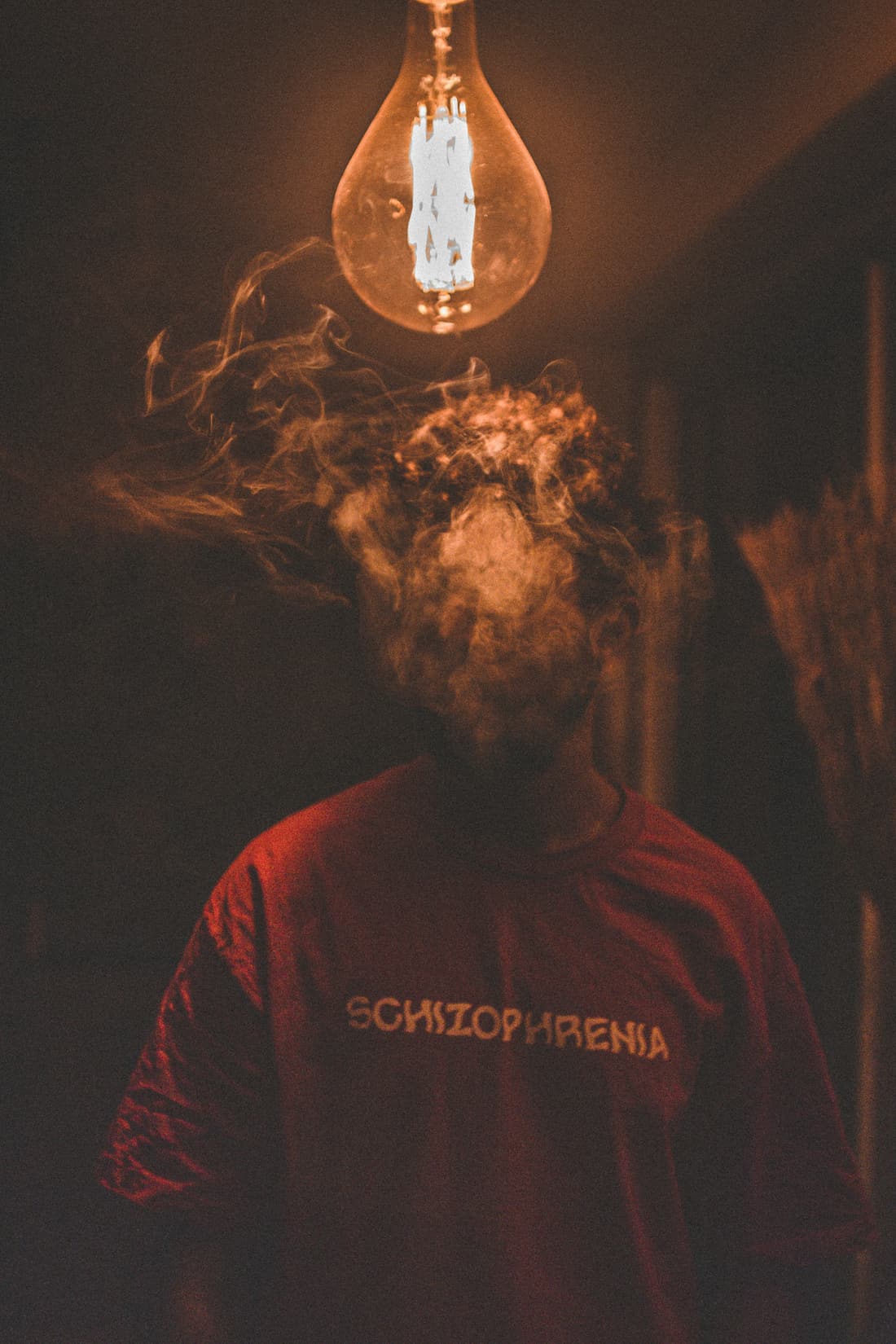 A figure beneath a glowing bulb and a cloud of smoke